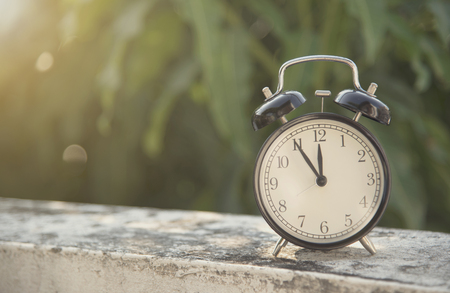 black alarm clock on table at morning in garden background.の写真素材