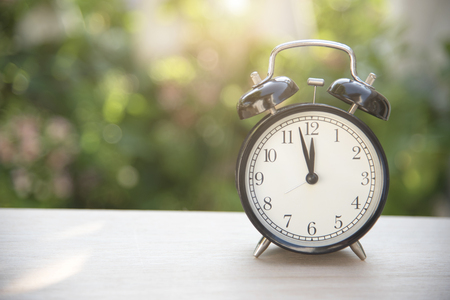 black alarm clock on table at morning in garden background.の写真素材
