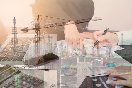Double exposure business worker with graph finance and factory construction on desk office. concept plan investment.の写真素材