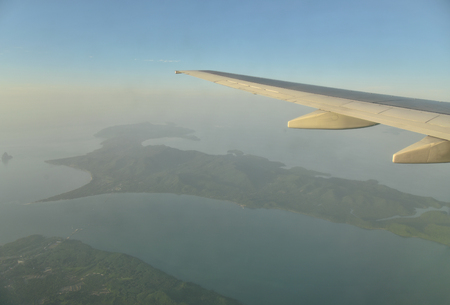 Wing of an airplane flying above sea view and sunrise.の写真素材