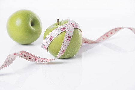 green apple with measure tape on white background. concept nutrition healthy.の写真素材
