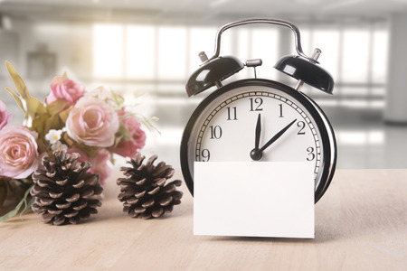 blank paper note with alarm clock on wood table with copy space for text display montage.