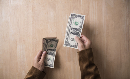 businessman hand holding dollar on wooden table in office. concept offer money finance.