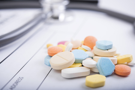 Pharmacy background on table. Stethoscope and prescription paper with colorful medicine.