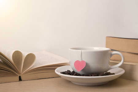 tea cup with red heart on book shelf. Valentines day vintage background.の写真素材