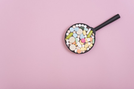 colorful medicine on magnifying glass pharmacy on pink background. の写真素材