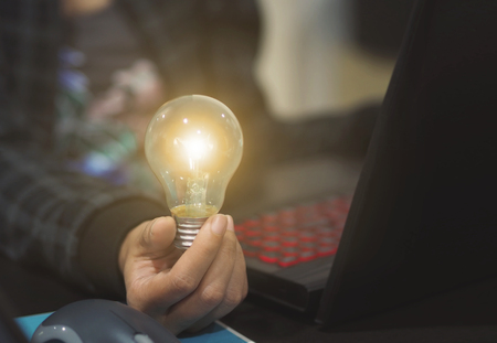 hand holding light bulb. concept teamwork ideas with innovation and creativity.の写真素材