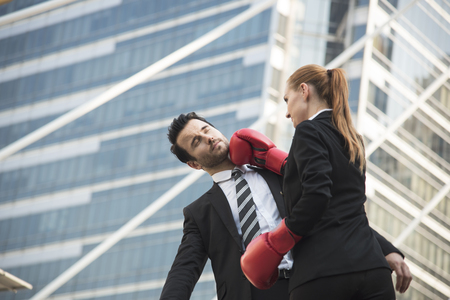 Two competitive businessperson and boxing gloves attacking one another. concept fight for business.