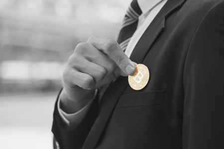 businessman holding gold bitcoin from suit pocket.の写真素材
