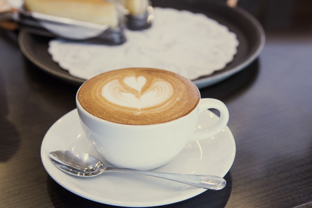 closeup hot coffee latte art cup on wood table.の写真素材