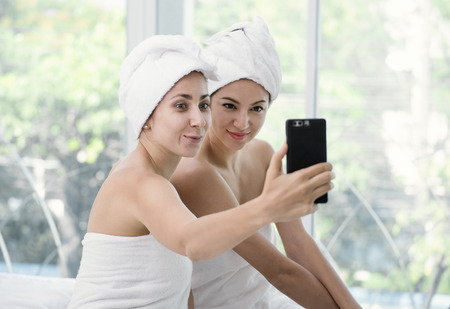 beautiful young woman relaxing using smartphone selfie in spa salon.の写真素材
