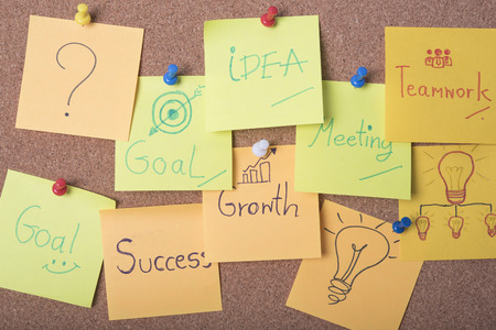 Meeting and idea text on sticky note or post is on cork bulletin billboard.