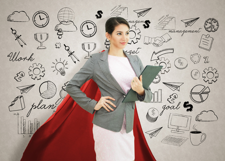 Young confident business superhero woman wearing red cape against with strategy background. concept point to future.の写真素材