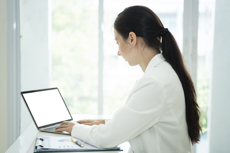 Businesswoman working on laptop computer with empty white screen for montage.の写真素材