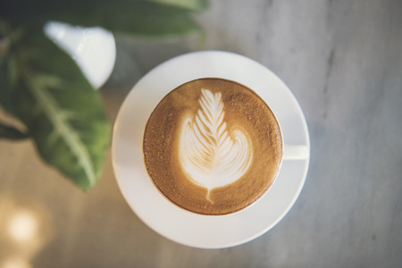 latte or Cappuccino with frothy foam, coffee cup top view on table in cafe.