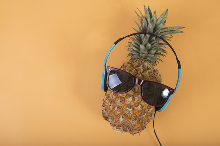 Pineapple with sunglasses and headphone on orange background. fruit summer concept.の写真素材