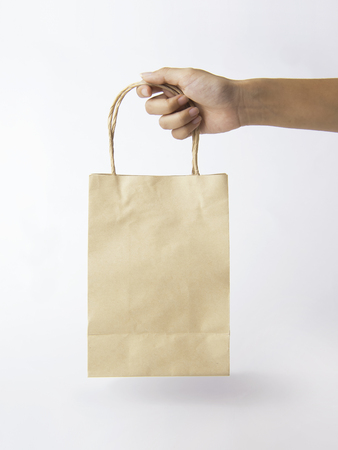 Hand holding Blank brown paper bag for mockup template advertising and branding background. の写真素材