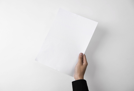 hand showing blank paper A4 flyer for mockup template design branding on grey background.の写真素材