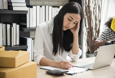 Young woman sitting in a home office with her laptop, Stressful for work.の写真素材