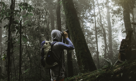 traveler photographing with backpack and enjoying a beautiful nature forest.の写真素材