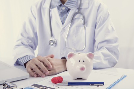 Doctor and piggy bank on table medical fee for health care. finance and insurance concept.の写真素材