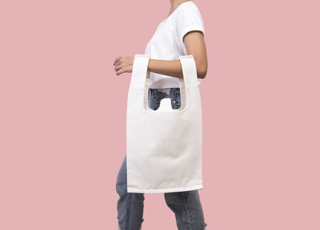 Girl is holding bag canvas fabric for mockup blank template isolated on pink background.