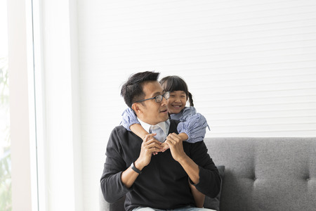 Asian father and daughter playing and hug together in livingroom at home.の写真素材