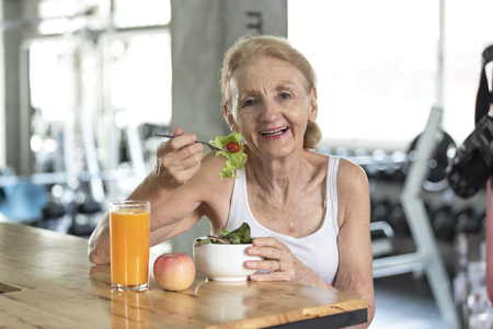 Senior woman eating healthy salad and orange juice. elderly health lifestyle concept.の写真素材