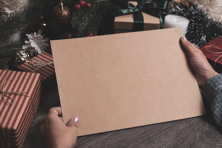 Christmas holiday greeting paper design mockup with decoration on wood table.の写真素材