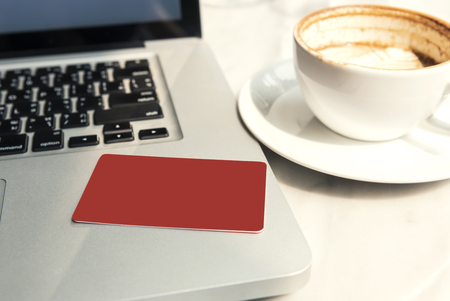 mockup red credit card on laptop computer in coffee shop. Online shopping concept.の写真素材