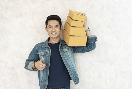 happy asian young delivery man standing with parcel post box on white background.