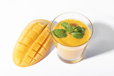 Fresh mango smoothie and ripe mango slice on white background. summer drink.の写真素材