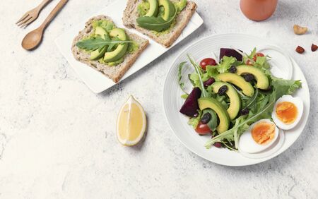 Fresh healthy vegetable salad with egg, tomato, avocado, spinach, lettuce in plate on table background.の写真素材
