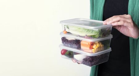 Hand holding fresh healthy diet lunch box with vegetable salad on white background with copy space.の写真素材