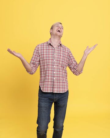 Laugh young man wearing red plaid shirt standing isolated over yellow background.の写真素材