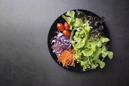 Fresh healthy vegetable salad with tomato, cucumber, spinach, lettuce in plate on table background.の写真素材