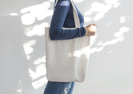 Girl is holding bag canvas fabric for mockup blank template on sunlight background.  global warming...