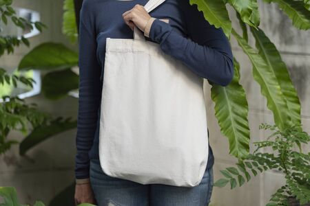 Girl is holding bag canvas fabric for mockup blank template on nature background.  global warming...
