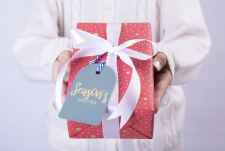 women hand holding red gift box and paper tag isolated on white background for christmas and new year concept.の写真素材