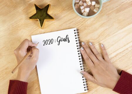 Hand writing mockup postcard for goals to do list on wooden background.Christmas and Happy new year resolution concept.の写真素材