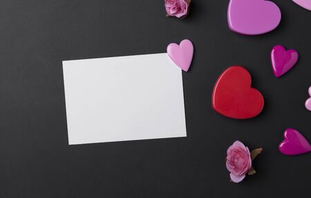 Valentines day background with red hearts and postcard on black copy space background.