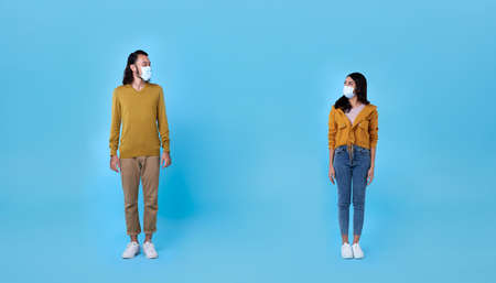 Asian man and woman character wearing surgical face mask maintain social distancing to prevent from...