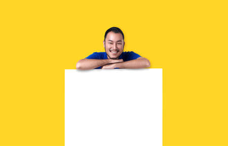 Smiling young Asian man with empty speech bubble studio shot on yellow background.