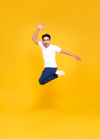 Young happy handsome Asian man jumping isolated over yellow background.
