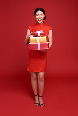 Happy Chinese new year. Asian woman wearing traditional cheongsam qipao dress holding gift box...