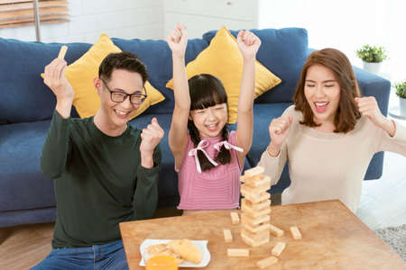 Happy Asian family having fun playing Jenga game in the living room at home.の写真素材