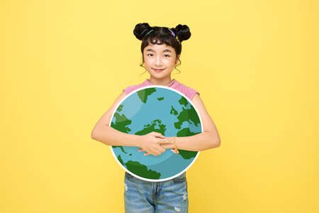 Happy Asian cute girl schoolgirl hug globe isolated on yellow background. World environment day...