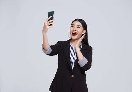 Happy and friendly face asian businesswoman smile in formal suit her using smartphone has a video...