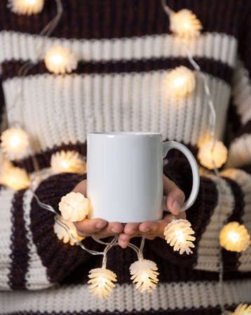 women hand holding white ceramic coffee cup with light decoration. mockup mug for creative advertising text message or promotional content.の写真素材