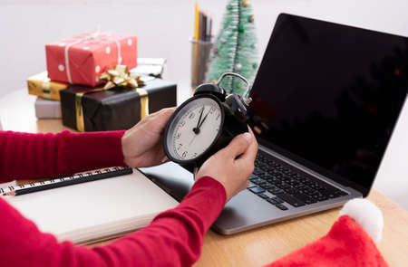 Businesswoman holding a clock countdown new year on office table in new year day 2022.
